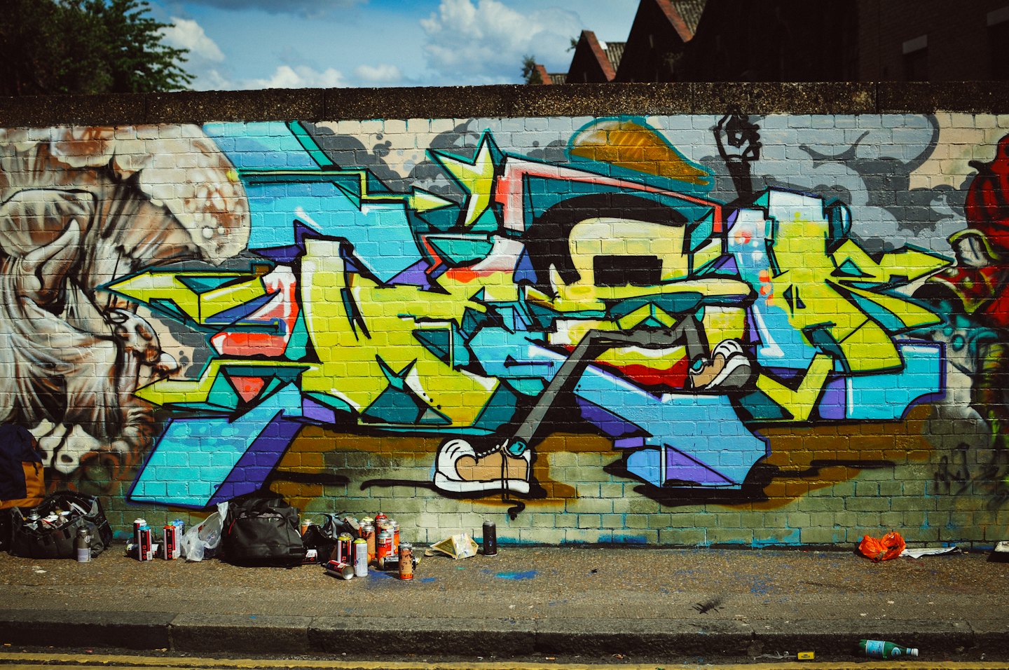 Sprühdosen liegen vor einer Graffitiwand auf dem Boden.
