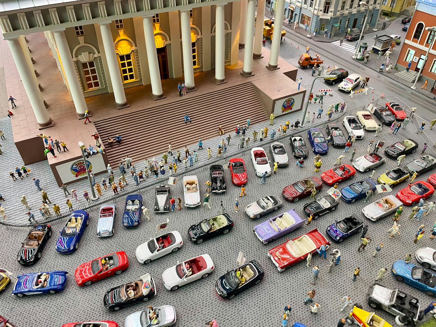 Winzige Menschen und Autos bevölkern eine detaillierte Stadtstraßen-Diorama.
