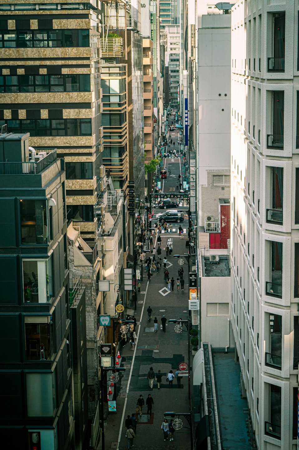 Menschen und Autos in einer belebten Stadtstraße mit modernen Gebäuden.