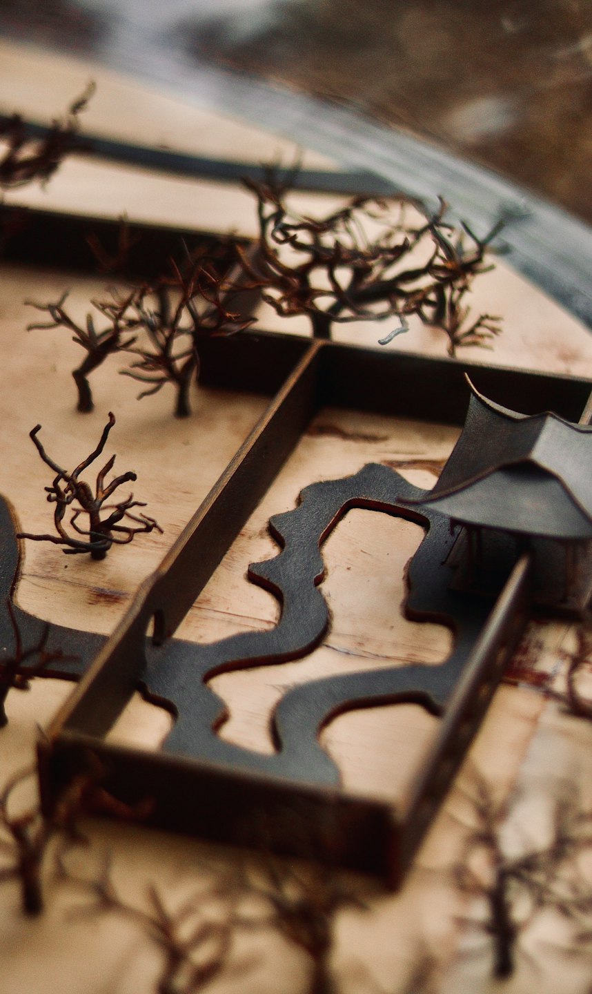 Miniatur-Architekturmodell mit Drahtbäumen auf Holzsockel.