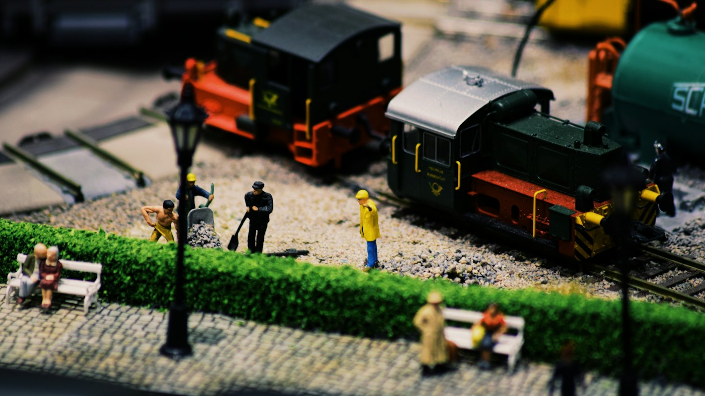 Miniatur-Modelleisenbahn-Diorama mit winzigen Figuren und Zügen.