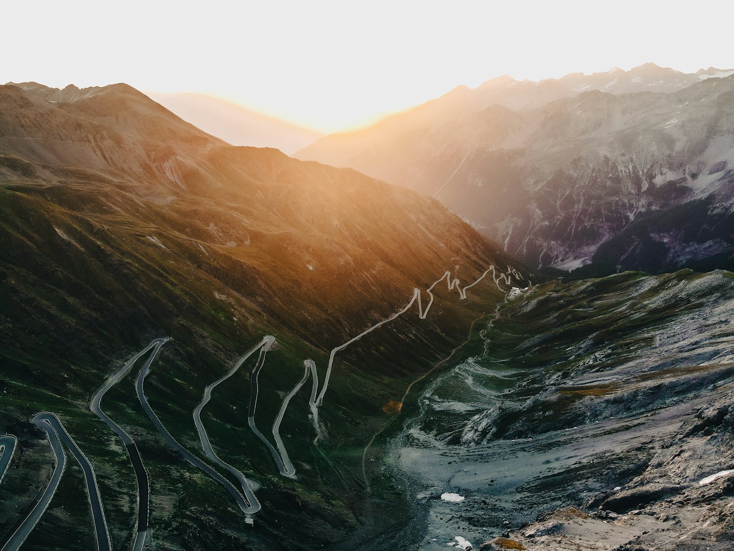 Eine kurvenreiche Straße schlängelt sich durch ein raues Gebirgstal.