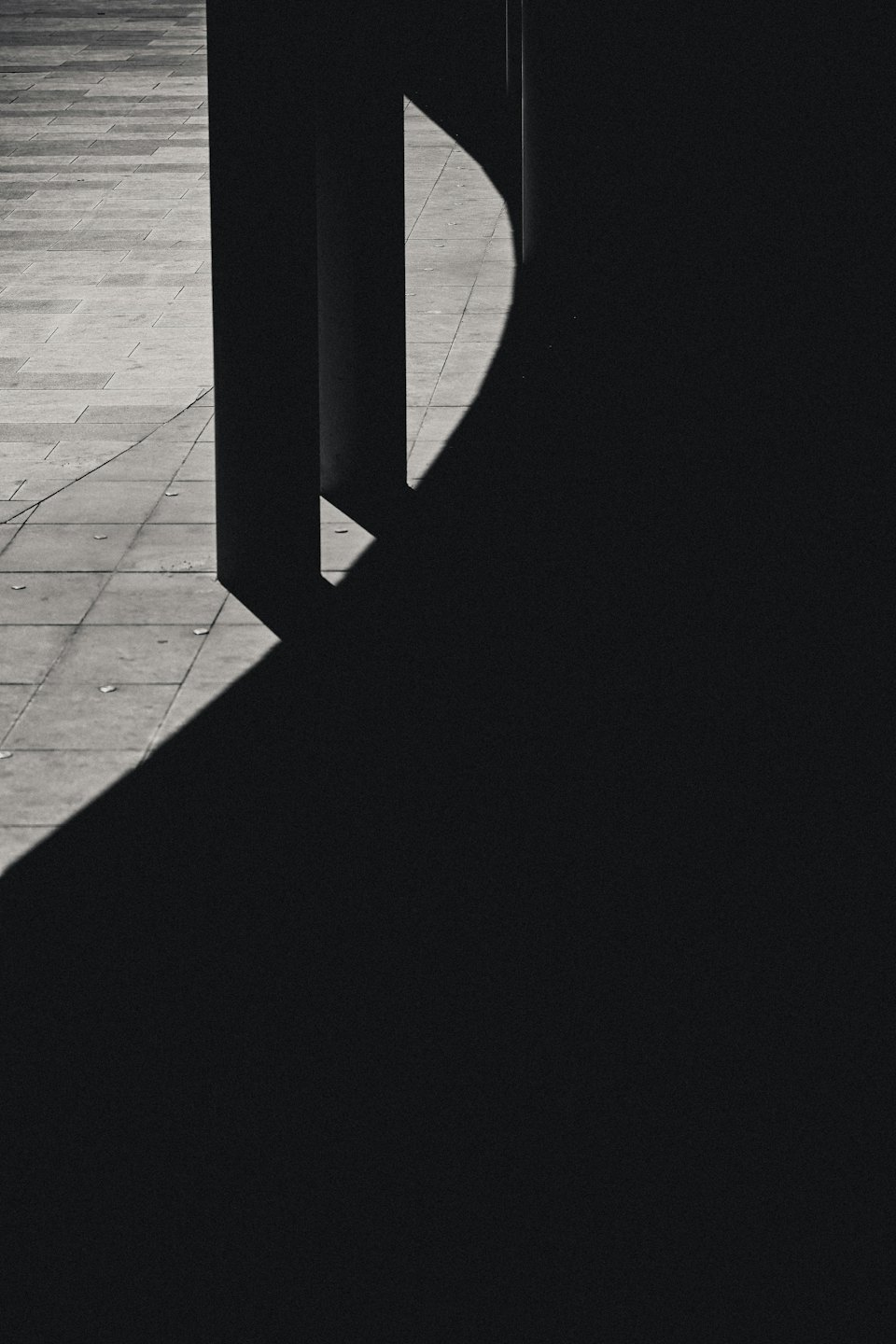 Geometrische Schatten fallen auf hellgrauen Fliesenboden.